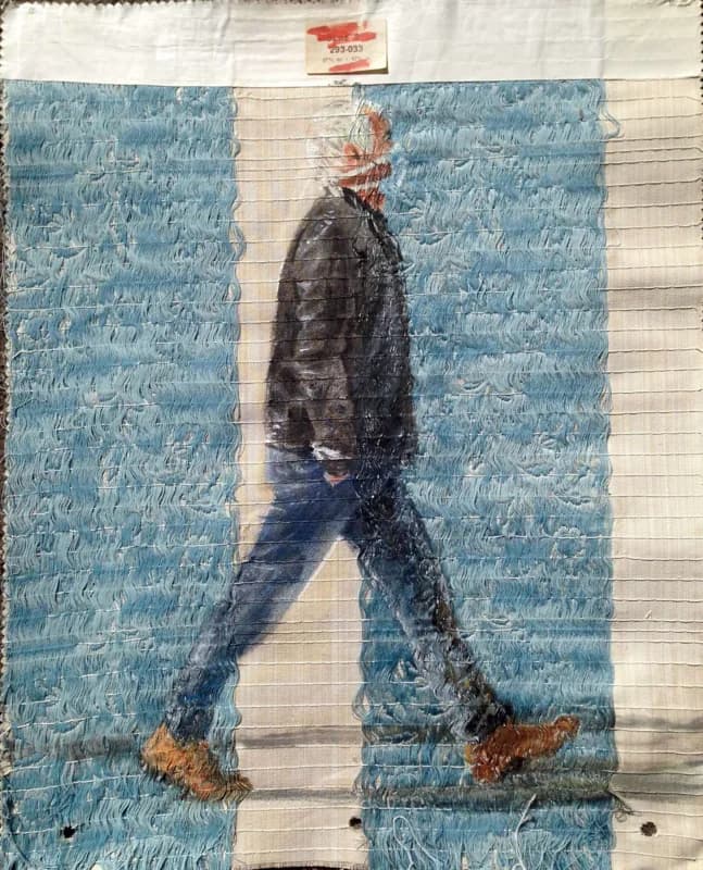 Figura maschile di profilo, con giacca nera, jeans e scarpe marroni, ritratta mentre cammina verso destra su un tessuto azzurro a motivo vegetale, attraversato da una larga fascia verticale bianca. In alto, su una fascia bianca, compare un piccolo rettangolo rosso e bianco.